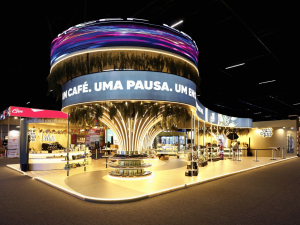 Visão frontal do estande Café com Deus Pai com testeira em painel de LED circular e iluminação cênica na Bienal do Livro.