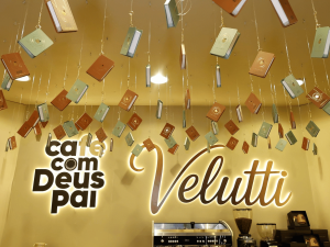 Instalação cenográfica de livros suspensos sobre o teto do espaço de café